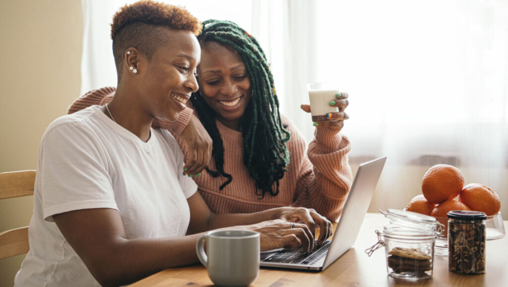 two women smiling while on a laptop