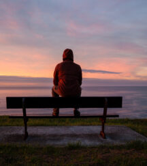 man sitting on bench overlooking the ocean