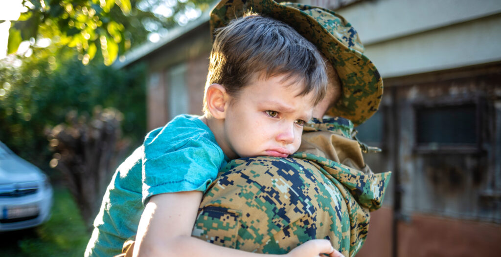 Child saying tearful goodbye to military parent before deployment